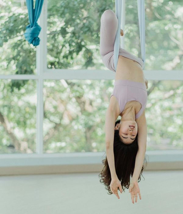 Person stretching gracefully in a bright, sunlit room, showing flexibility.